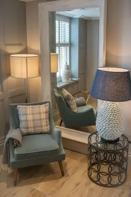 a living room with a chair and a lamp and a mirror at Freemasons at Wiswell in Whalley