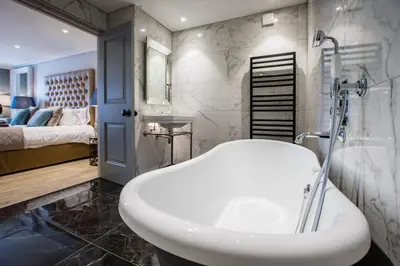 a bathroom with a white sink and a bedroom at Freemasons at Wiswell in Whalley
