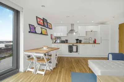 a kitchen and living room with a table and chairs at GuestReady - Stylish Flat with Bay View in Liverpool