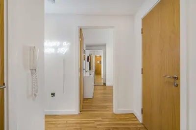a hallway with white walls and a wooden door at GuestReady - Stylish Flat with Bay View in Liverpool