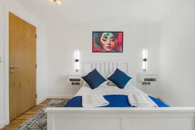 a bedroom with a large white bed with blue pillows at GuestReady - Stylish Flat with Bay View in Liverpool