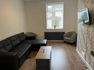 a living room with a black couch and a table at Spacious, Modern 4BR House, LFC, Free Parking in Liverpool