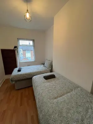 a bedroom with two beds and a window at Spacious, Modern 4BR House, LFC, Free Parking in Liverpool