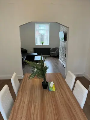 a living room with a wooden table and white chairs at Spacious, Modern 4BR House, LFC, Free Parking in Liverpool