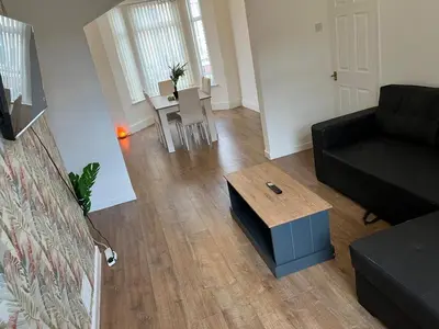 a living room with a black couch and a coffee table at Spacious, Modern 4BR House, LFC, Free Parking in Liverpool