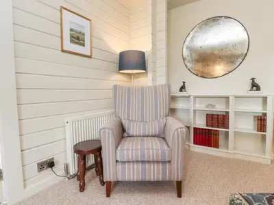 a living room with a chair and a lamp at Manor Lodge in Clitheroe