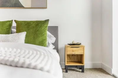 a white bed with green pillows next to a night stand at Verona Apartment - City Apartment - 2Bed 2Bath in Liverpool