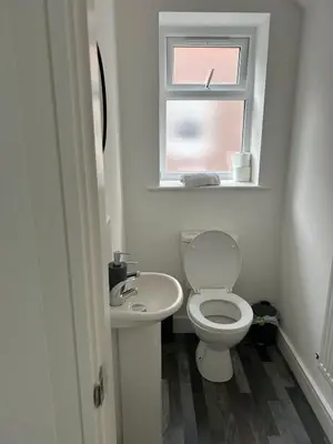 a bathroom with a toilet and a sink and a window at Spacious 4BR House with Backyard in Saint Helens in Saint Helens