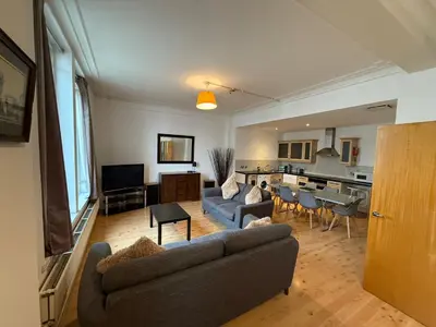 a living room with a couch and a kitchen at Large city centre apartment in Liverpool