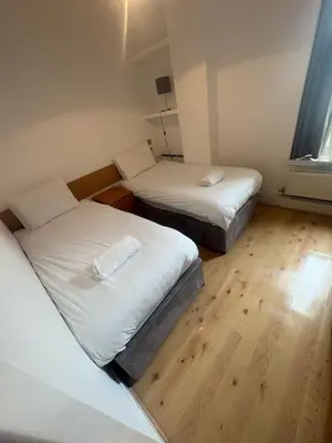 two twin beds in a small room with wooden floors at Large city centre apartment in Liverpool