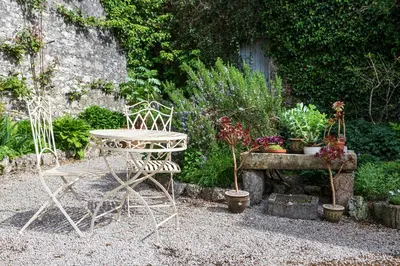 a table and chairs in a garden with potted plants at Haverbrack Country House in Beetham