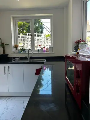 a kitchen with white cabinets and a sink and two windows at Luxury 4 Bed Home Sleeps 9, Games Room, Parking