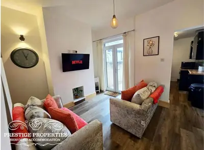 a living room with two couches and a clock on the wall at 12 Romney Road by Prestige Properties SA in Barrow in Furness