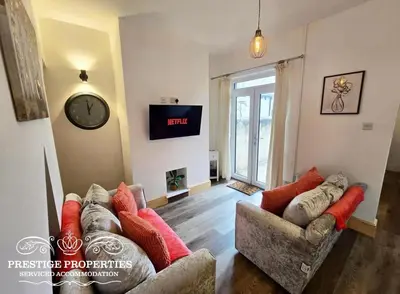 a living room with two couches and a clock on the wall at 12 Romney Road by Prestige Properties SA in Barrow in Furness
