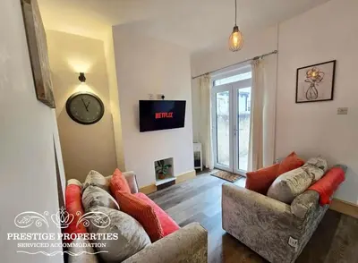 a living room with a couch and a clock on the wall at 12 Romney Road by Prestige Properties SA in Barrow in Furness