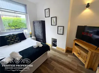 a bedroom with a bed and a television and a window at 12 Romney Road by Prestige Properties SA in Barrow in Furness