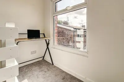 a room with a desk and a window with a laptop at Quaint Studio Apartment Near To Waterfront in Wallasey