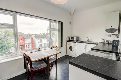 a kitchen with a table and a sink and a window at Quaint Studio Apartment Near To Waterfront in Wallasey