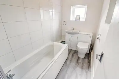 a white bathroom with a tub and a toilet at Quaint Studio Apartment Near To Waterfront in Wallasey