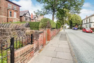 a street with a brick wall and a fence at Quaint Studio Apartment Near To Waterfront in Wallasey