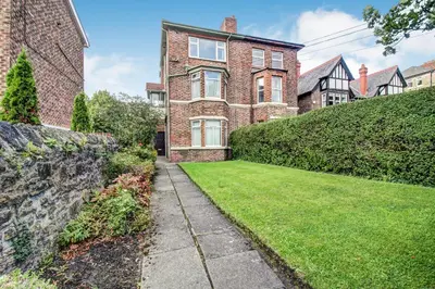 a brick house with a grass yard in front of it at Quaint Studio Apartment Near To Waterfront in Wallasey