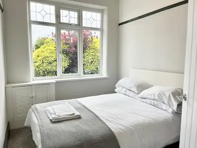 a white bedroom with a bed and two windows at Cosy Bungalow & Peaceful Garden in Halsall