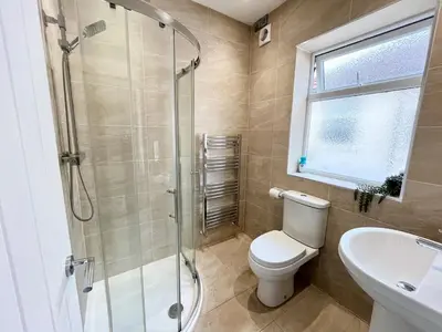 a bathroom with a shower and a toilet and a sink at Cosy Bungalow & Peaceful Garden in Halsall