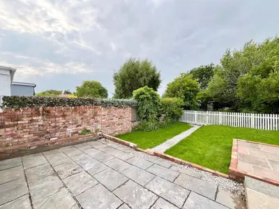 a garden with a brick fence and a yard at Cosy Bungalow & Peaceful Garden in Halsall