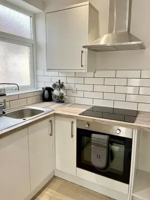 a white kitchen with a sink and a dishwasher at Cosy Bungalow & Peaceful Garden in Halsall
