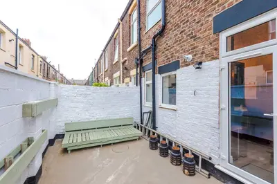 a green bench sitting next to a building at Stunning & Spacious Home by 53 Degrees Property, Sleeps 7 in the heart of Anfield! in Liverpool