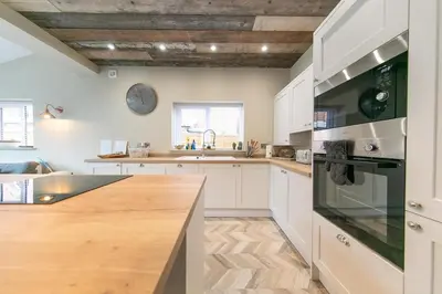 a kitchen with white cabinets and a wooden counter top at Villa Rose-Spacious Home with beautiful garden in Lytham St Annes