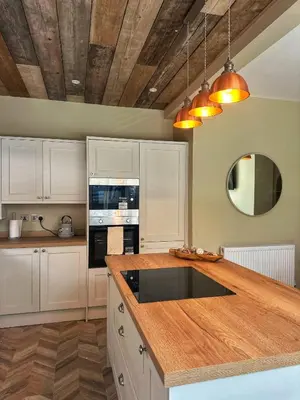 a kitchen with white cabinets and a wooden counter top at Villa Rose-Spacious Home with beautiful garden in Lytham St Annes
