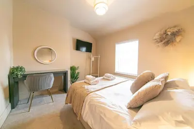 a bedroom with a bed with a chair and a window at Villa Rose-Spacious Home with beautiful garden in Lytham St Annes