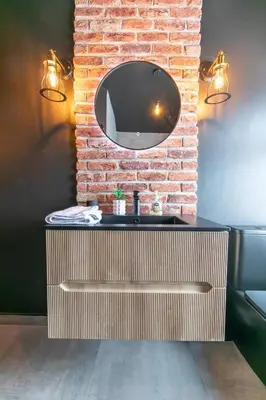 a bathroom with a sink and a mirror on a brick wall at Villa Rose-Spacious Home with beautiful garden in Lytham St Annes