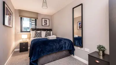 a bedroom with a bed and a large mirror at Stylish Liverpool Apartment with Parking & Balcony in Liverpool
