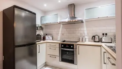 a kitchen with a stainless steel refrigerator and white cabinets at Stylish Liverpool Apartment with Parking & Balcony in Liverpool