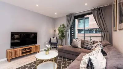 a living room with a couch and a tv at Stylish Liverpool Apartment with Parking & Balcony in Liverpool