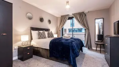 a bedroom with a large bed and a television at Stylish Liverpool Apartment with Parking & Balcony in Liverpool