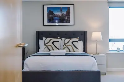 a bed with a black headboard in a bedroom at Waterfront Penthouse with Balcony & Parking in Liverpool
