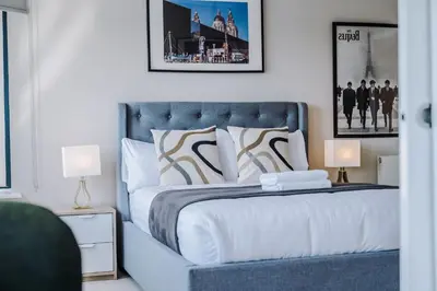 a bedroom with a blue bed with two lamps at Waterfront Penthouse with Balcony & Parking in Liverpool
