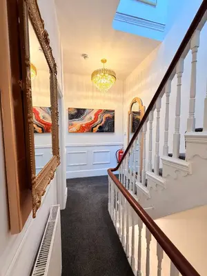 a hallway with stairs with a mirror and a chandelier at Vance Holiday Home in Blackpool