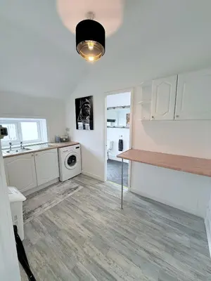 a kitchen with white cabinets and a washer and dryer at Vance Holiday Home in Blackpool