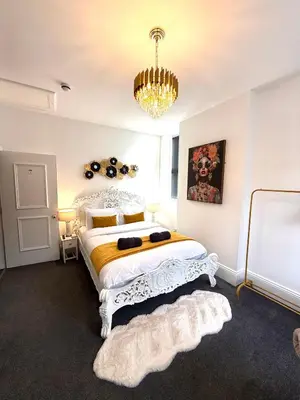 a bedroom with a large white bed with a chandelier at Vance Holiday Home in Blackpool