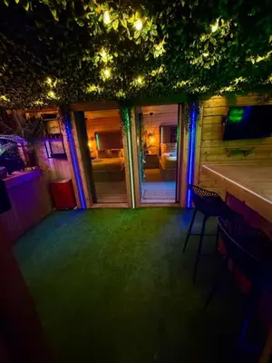 a room with a bar and a room with blue lights at Woodland Escapes Glamping - Utopia