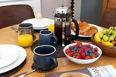 a table with a breakfast of fruit and orange juice at Curlew Loft in Lancaster