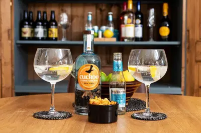 two wine glasses and a bottle of alcohol on a table at Curlew Loft in Lancaster