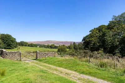 a field with a fence and a dirt road at Curlew Loft in Lancaster