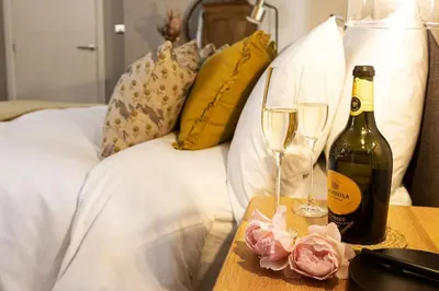 a bottle of wine and two glasses on a table at Hen Harrier Lodge in Lancaster