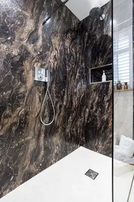 a bathroom with a shower with a black marble wall at Hen Harrier Lodge in Lancaster