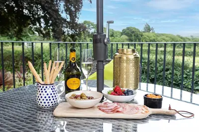 a table with a plate of food and a bottle of wine at Hen Harrier Lodge in Lancaster